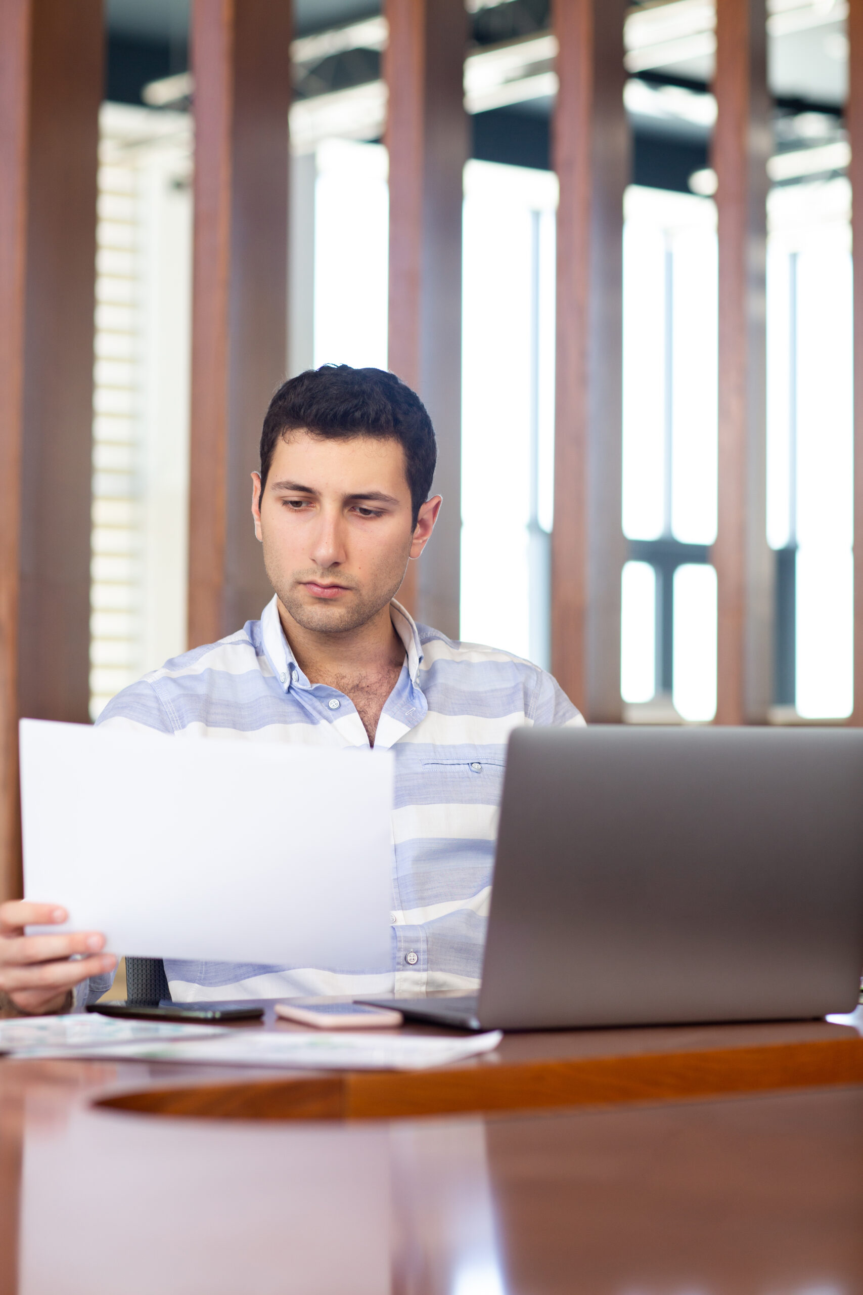 Inicio front view young handsome man striped shirt working inside conference hall using his silver laptop looking through documents daytime work activity building